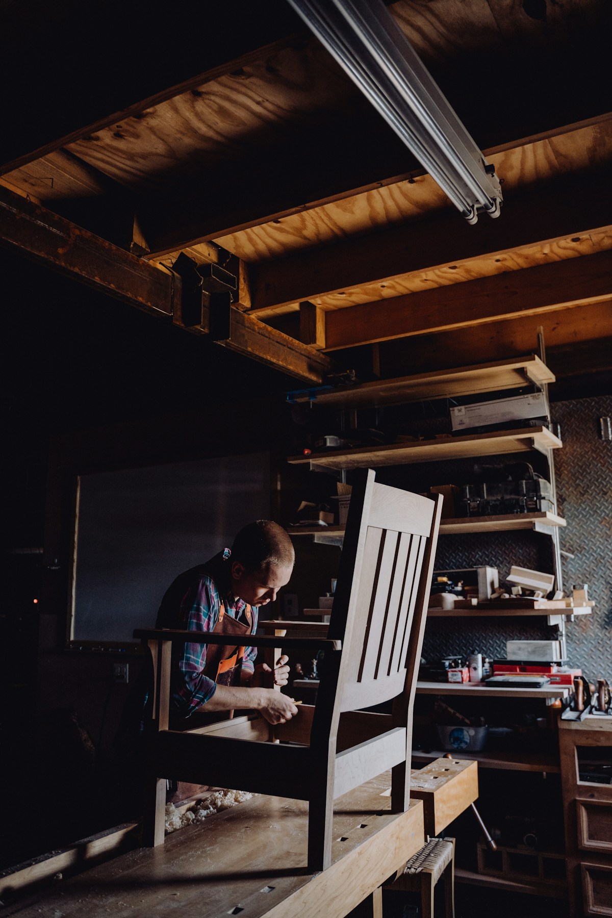 Carpenter sanding a timber chair in the workshop